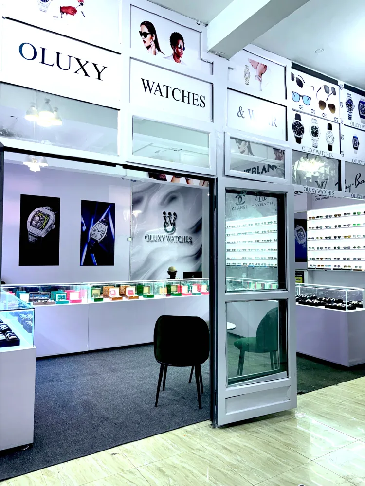 The front of the Oluxy Watches & Wear shop at GF Plaza: the white sign over the door, watch posters and lit glass counters inside, sunglasses on the wall to the right